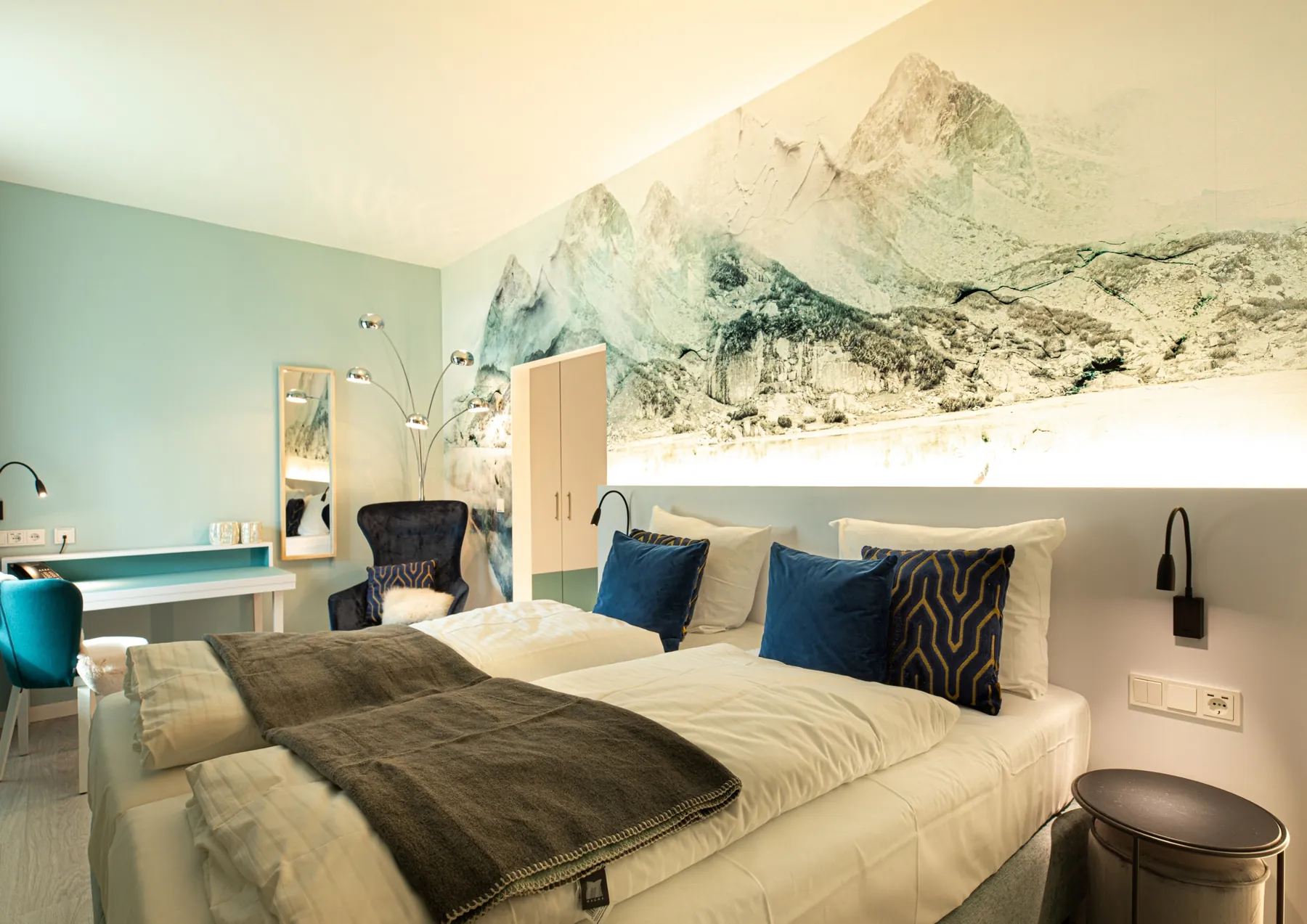 Hotelzimmer „Arktis“ mit Berg-Wandbild und blauen Akzenten im Hotel am Zoo Neunkirchen