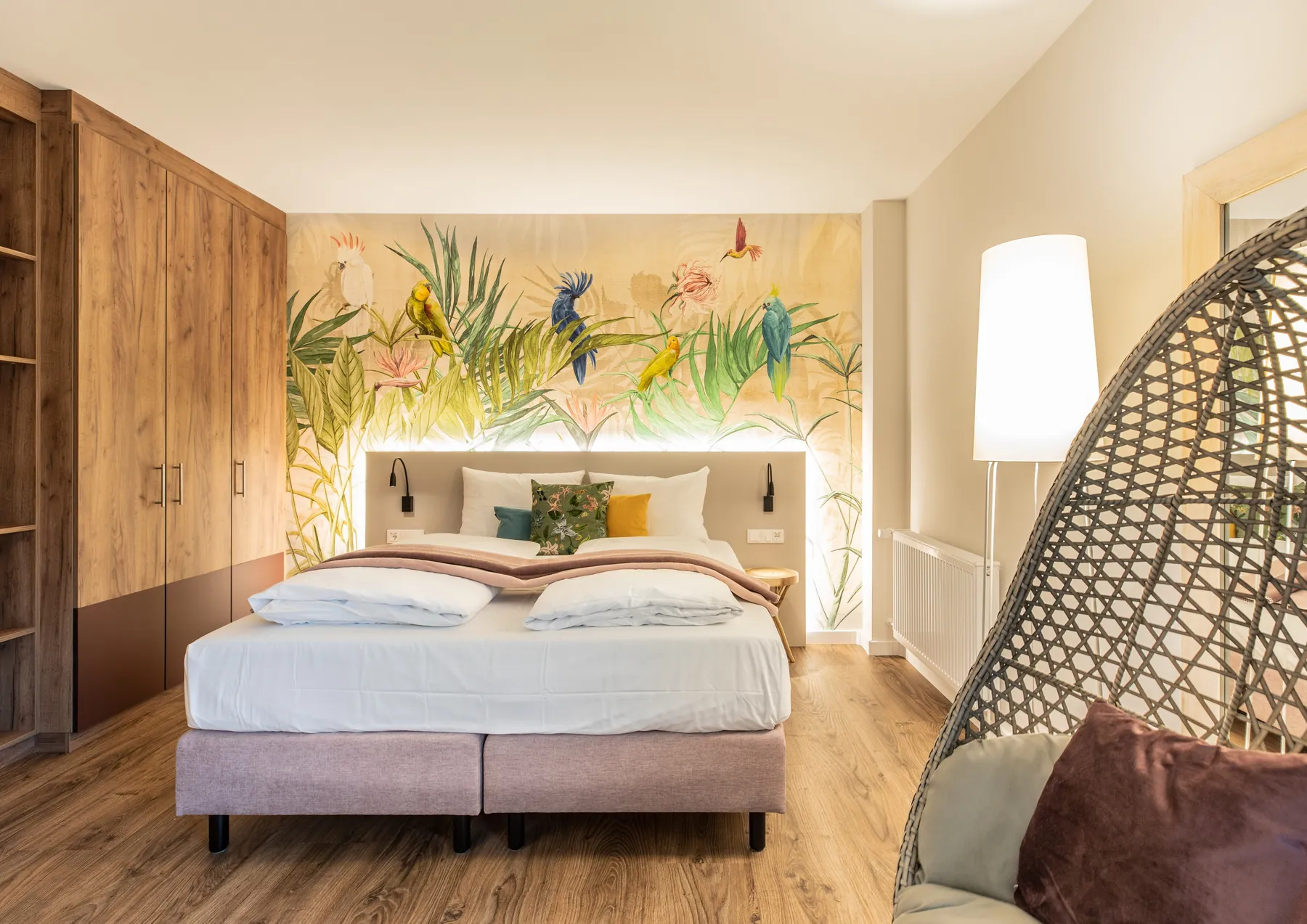 Hotelzimmer „Vogelwelt“ mit Vogel-Wandbild und Hängesessel im Hotel am Zoo Neunkirchen