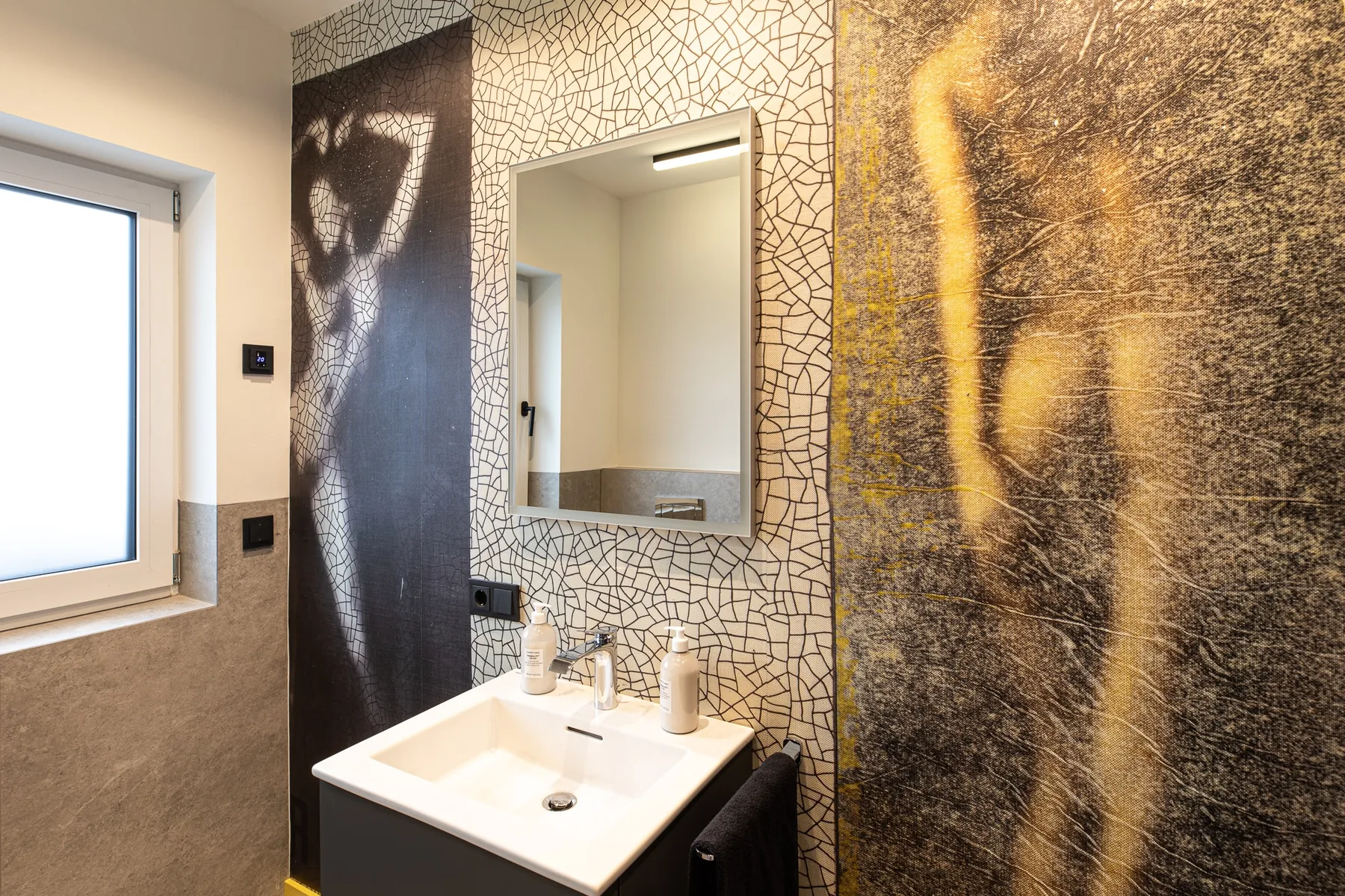 Gästebad mit schwarzem Waschtisch und Figurenmotiv an der Wand im Penthouse Black & White