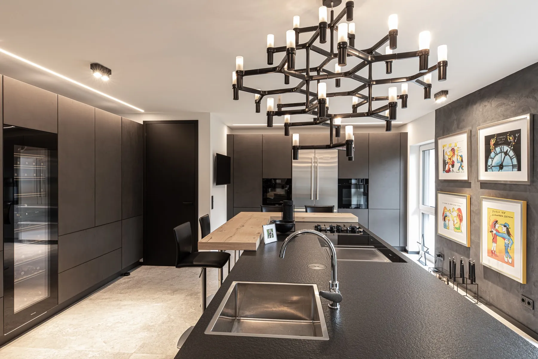 Küche mit schwarzen Fronten, Kochinsel und Kronleuchter im Penthouse Black & White