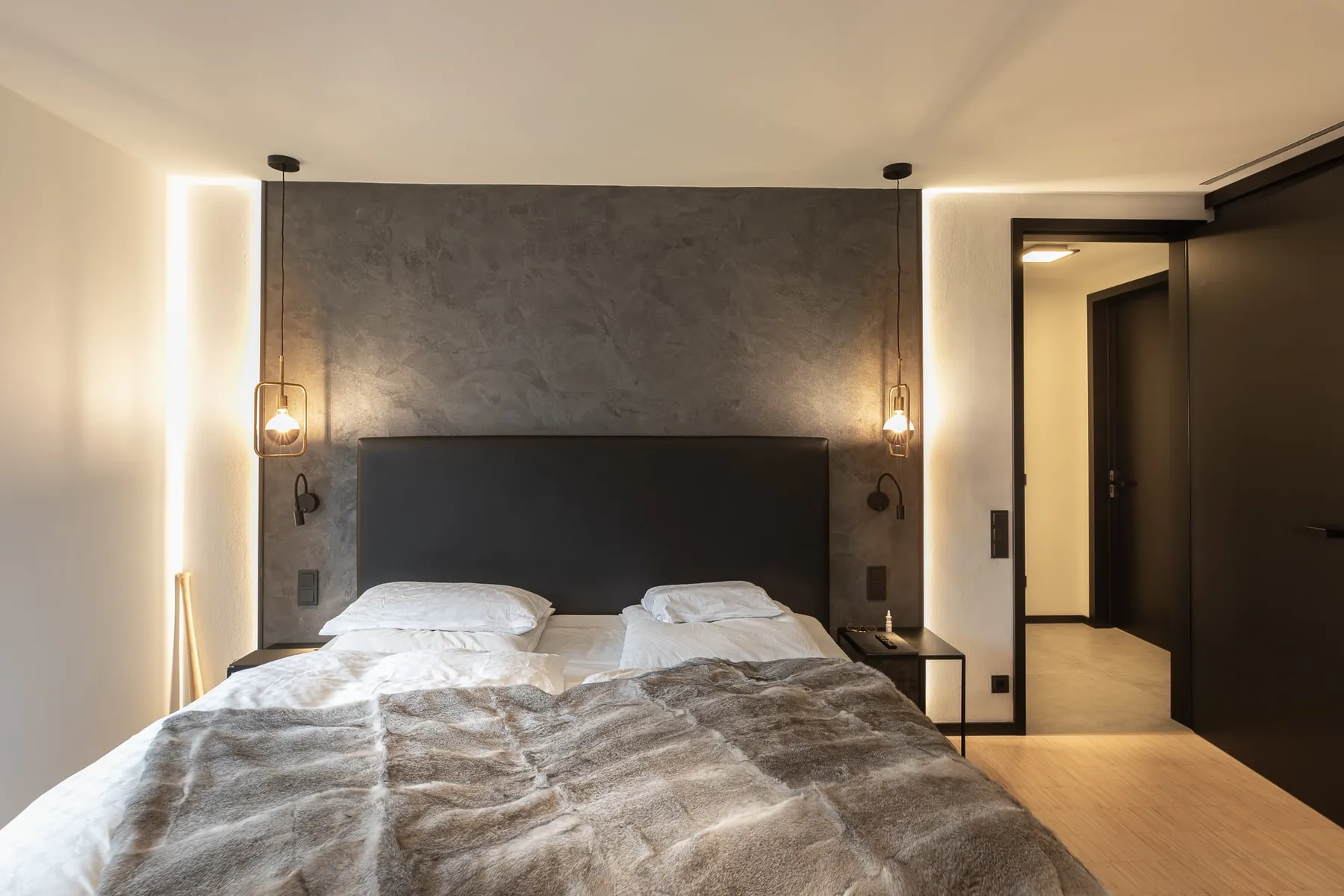 Schlafzimmer mit dunkler Wandverkleidung und indirektem Licht im Penthouse Black & White